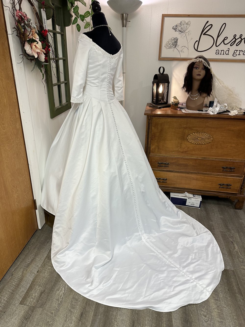 Back of "Ivy" Retro White Gown on a black manakin showing the train behind.