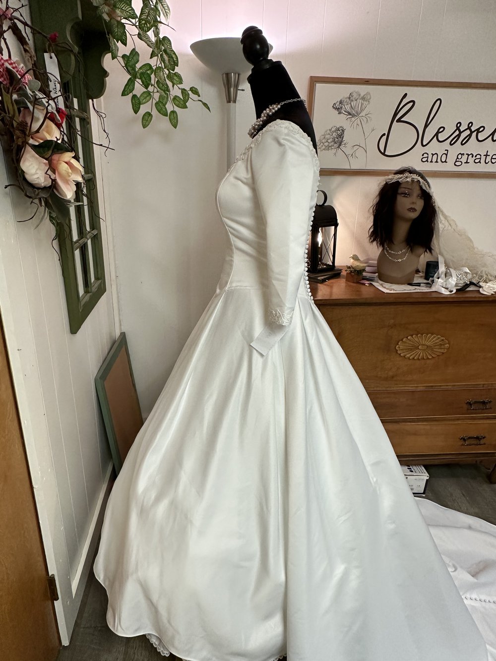 Side view of "Ivy" Retro White Gown on a black manakin with a necklace.